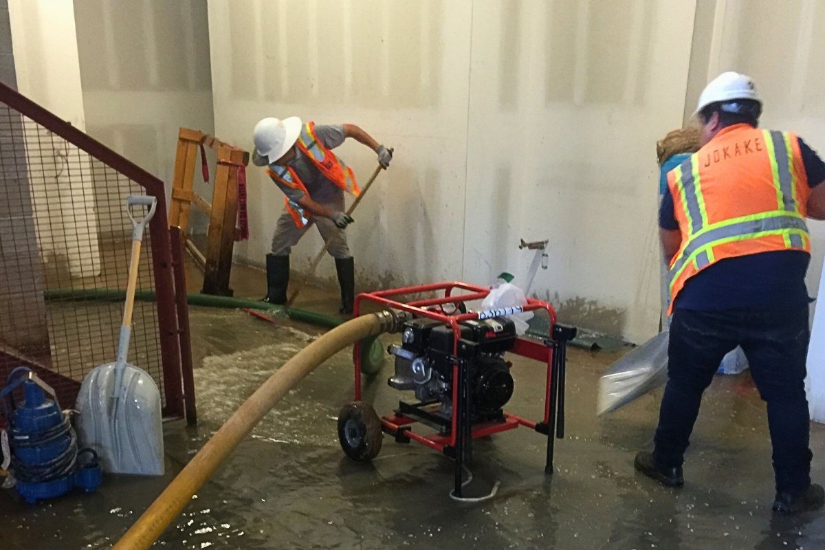 Restoration crew in hard hats and high-visibility vests pumping standing water out of a commercial building